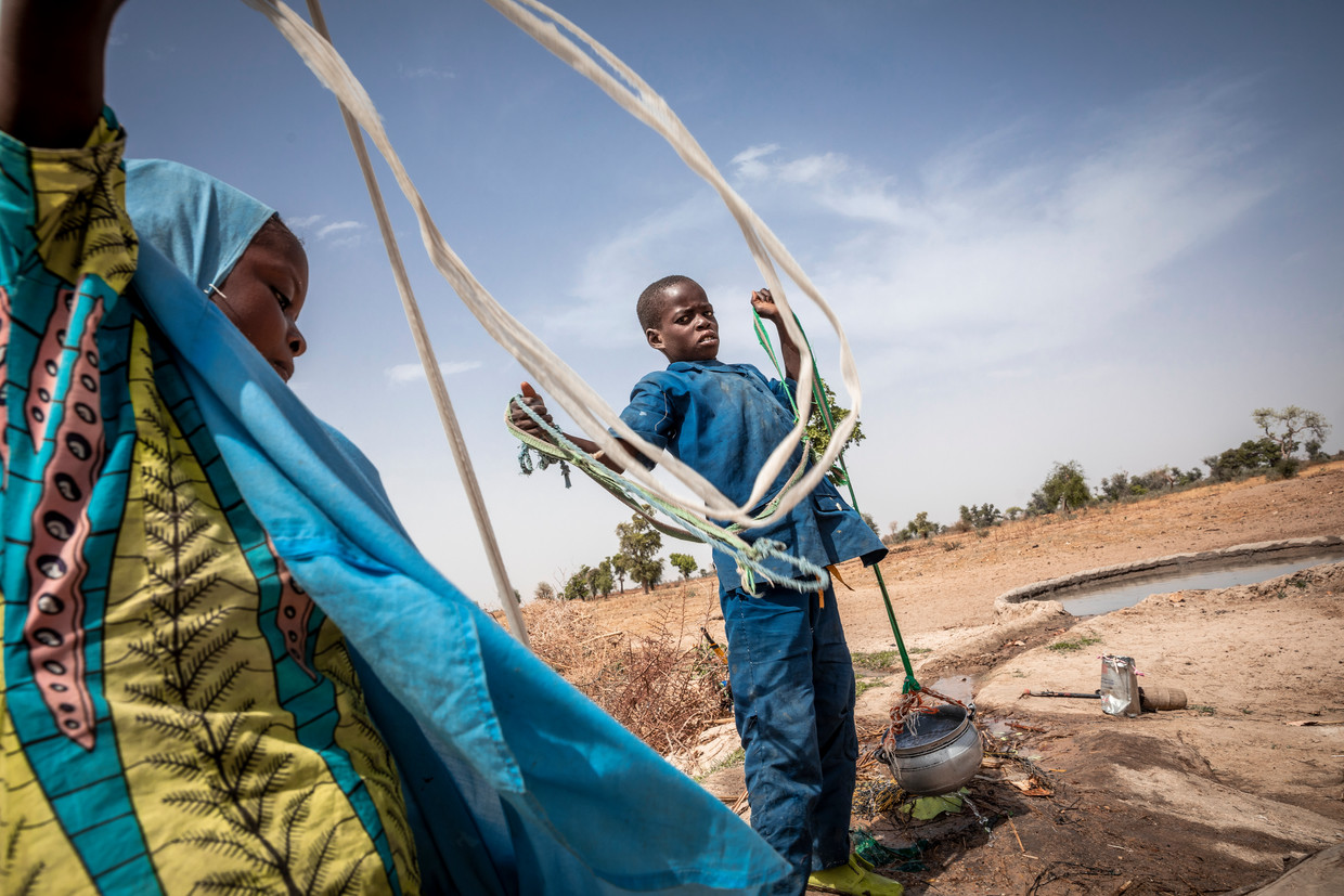 Kinderen halen water uit een zelf gegraven put in het kamp in Mémé, waar ontheemde Kameroeners en vluchtelingen uit Nigeria zijn neergestreken. Beeld 