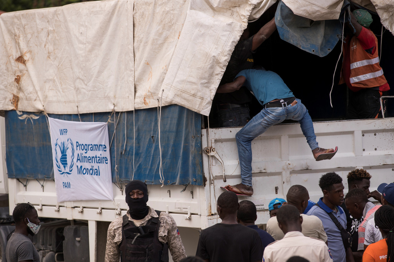 Een medewerker van het Wereld Voedsel Programma klimt op een truck om in Camp Perrin voedsel en water uit te delen aan slachtoffers van de aardbeving op Haïti. Zeker vier trucks van de hulporganisatie Food for the Poor werden vrijdag bestormd door wanhopige Haïtianen.