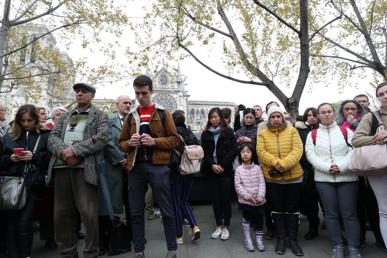 Mensen bidden bij de deels verwoeste Notre-Dame in Parijs.   Beeld REUTERS
