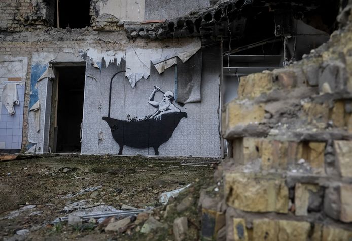 Een oudere man die een bad neemt op de muur van een verwoest gebouw in Horenka.