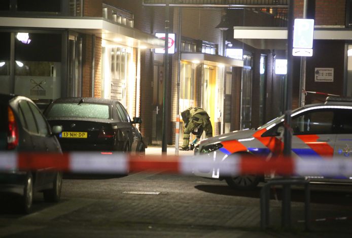Een medewerker van de EOD in beschermende kleding bekijkt de handgranaat in de Gasthuisstraat.