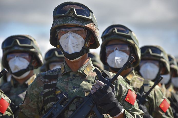 Chinese militairen met mondkapjes en speciale brillen op nemen deel aan de openingsceremonie.