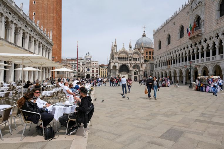 Mensen doen een terrasje op het San Marco-plein in Venetië. Italië blijft op dit moment dé trekpleister zonder rode zone. Beeld REUTERS