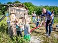 Wethouder Peter van de Noort knipt een lint door waarmee de schoolmoestuin van basisschool D'n Opstap in Lage Mierde officieel geopend is.