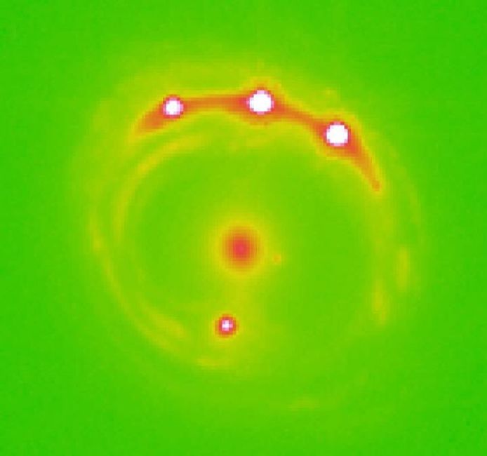 De gravitationele lens RX J1131-1231 is te zien in het midden, met vier