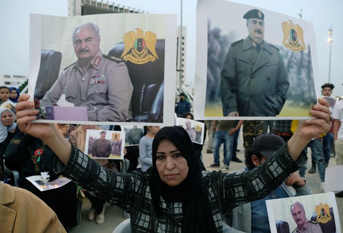 Een vrouw in de Libische stad Benghazi toont foto's van Khalifa Haftar bij een demonstratie tegen de regering in Tripoli.
