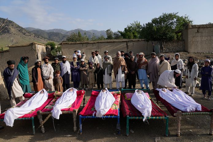 Afghanen staan bij de lichamen van hun familieleden die om het leven kwamen bij de aardbeving. In totaal overleden meer dan 1.000 mensen.