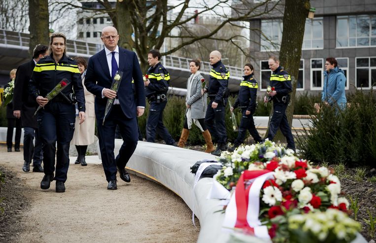 Minister Ferdinand Grapperhaus van Justitie en Veiligheid legt met politieagenten bloemen op het 24 Oktoberplein, de plek waar de tramaanslag plaatsvond. Vier mensen kwamen om het leven bij de aanslag. Beeld ANP