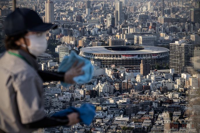 Een schoonmaker poetst een raam dat uitkijkt op het Olympic Stadium - kostprijs: 1,2 miljard euro - in Tokio. Vandaag beginnen daar officieel de Olympische Spelen.