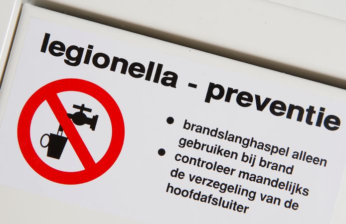 Sticker van Legionella Preventie op de kast waar de brandslang in een kantorenpand hangt.