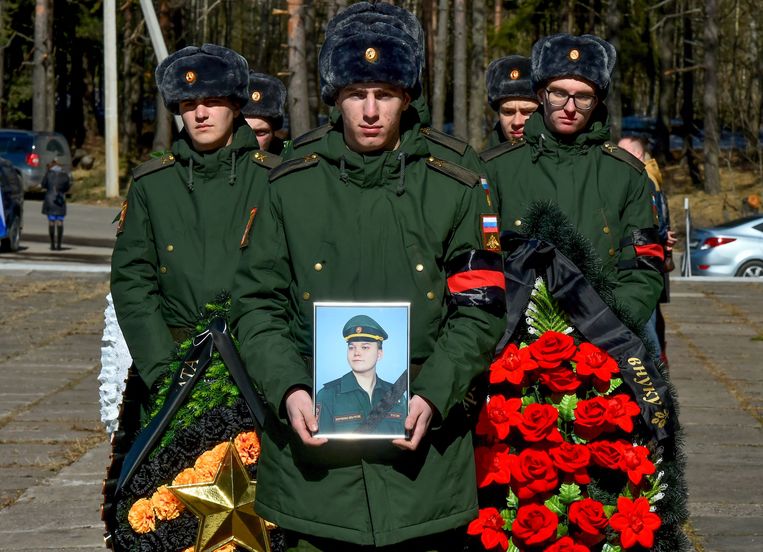 Russische soldaten dragen kransen en een foto van de twintigjarige Russische militair Nikita Avrov, tijdens zijn begrafenis in Loega, zo’n 150 kilometer ten zuiden van Sint-Petersburg op 11 april 2022. Hij stierf op 27 maart tijdens de Russische invasie van Oekraïne. Beeld AFP