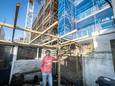 Jeroen Hooft in zijn achtertuin aan de Slagerstraat in Eindhoven met de nieuwbouwappartementen.