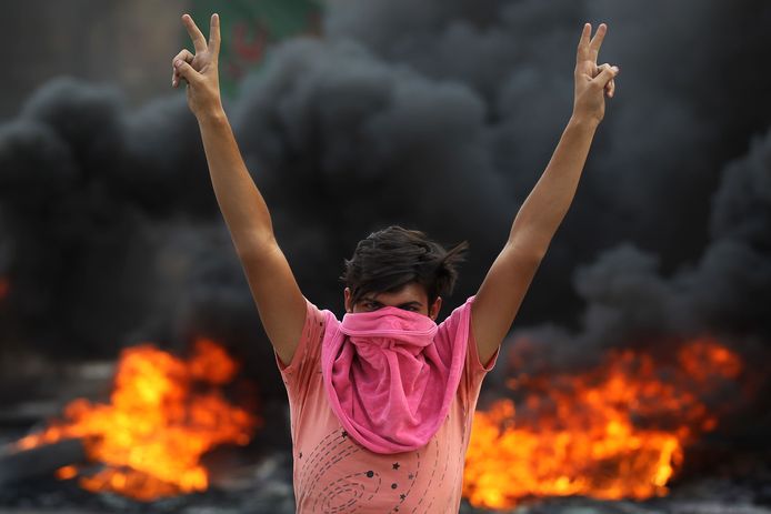 Een demonstrant maakt het vredesteken in Bagdad.