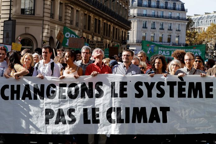Betogers lopen met een spandoek met de tekst: verander het systeem, niet het klimaat.