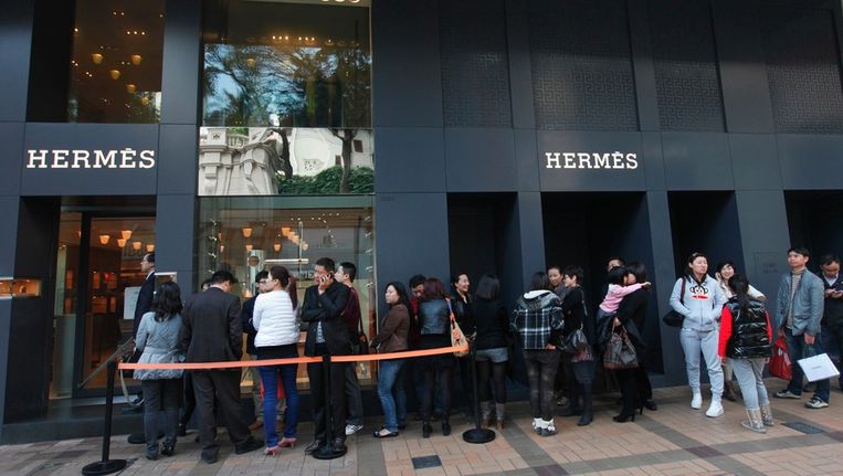 Chinezen staan in Hong Kong in de rij voor een winkel van Hermès. © ANP Beeld 