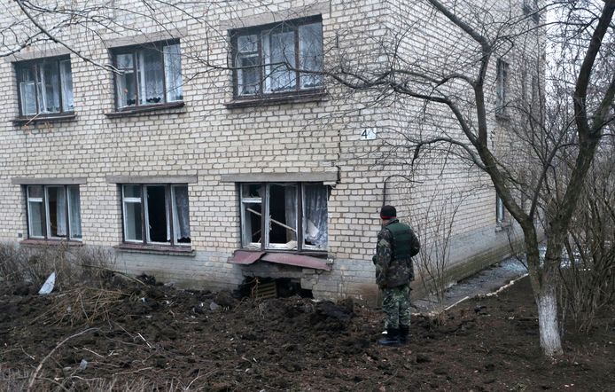 Een soldaat kijkt naar een beschadigd schoolgebouw in Artemivsk in Oekraïne.