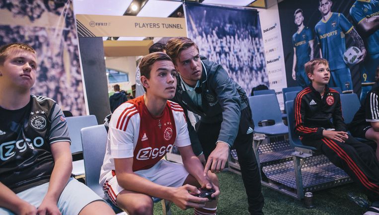 De door Ajax gecontracteerde e-sporter Koen Weijland geeft aanwijzingen aan een van de gelukkigen die voor het eerst FIFA 2017 mogen spelen in de pop-upstore in Amsterdam. Beeld Marcel Wogram
