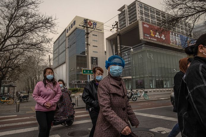 Mensen met mondmaskers tijdens de nieuwe zandstorm in Peking zondag.