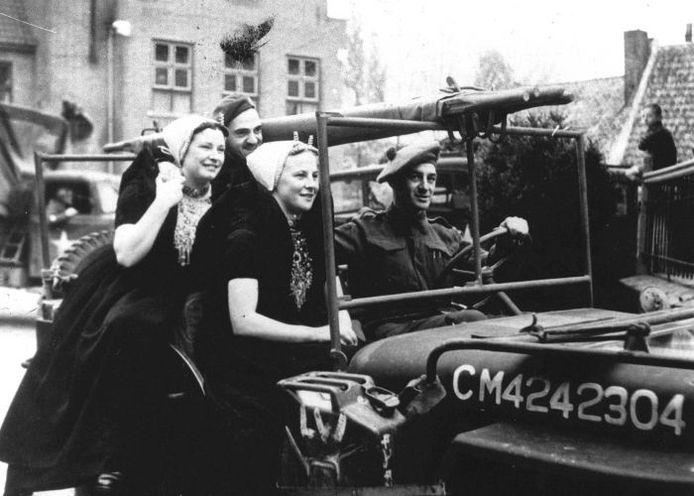 Twee vrouwen uit Zeeland rijden mee op een jeep van de geallieerden tijdens de intocht van de bevrijding van Nederland. Foto: ANP