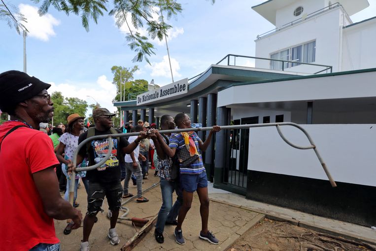 Mensen vallen de Nationale Assemblee aan tijdens een protest tegen het economische beleid van de regering in Paramaribo Beeld AFP