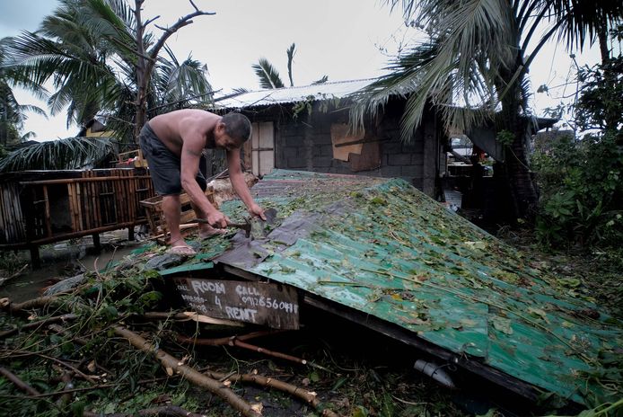 Een man herstelt het dak van zijn ingestorte huis na doortocht van tyfoon Kammuri op de Filipijnen.