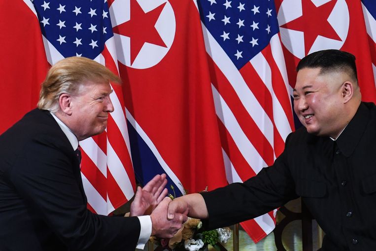 Donald Trump en Kim Jong Un schudden elkaar de hand. Beeld AFP