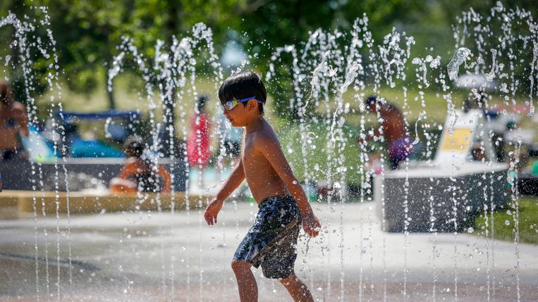 Een jongen zoekt verkoeling in een fontein in Calgary, Canada, in de zomer van 2021. Beeld AP