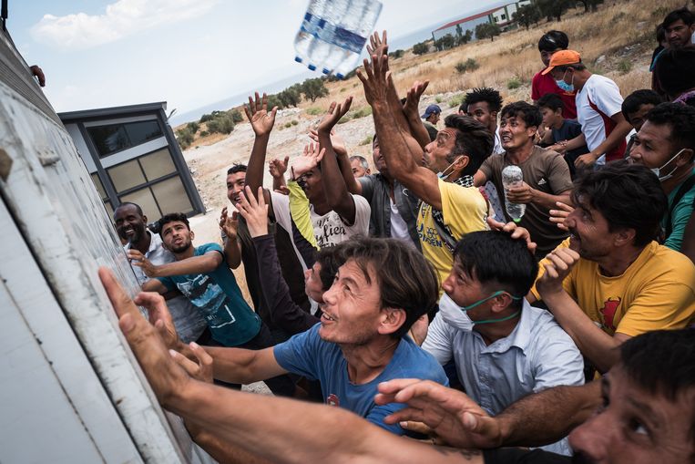 Vluchtelingen op Lesbos proberen een flesje water te bemachtigen. Beeld Nicola Zolin