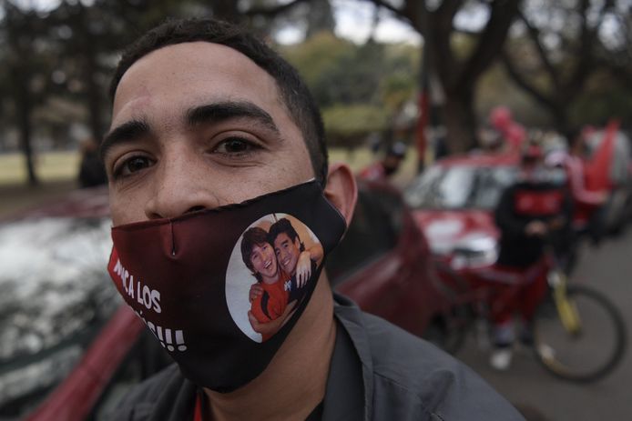 Een fan met mondmasker van Maradona en Messi.