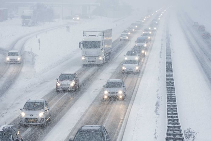 Auto's rijden in de sneeuw met aangepaste snelheid op de snelweg A-1 op de Hoge Veluwe. De winterse buien hebben delen van Nederland bedekt onder een witte deken.