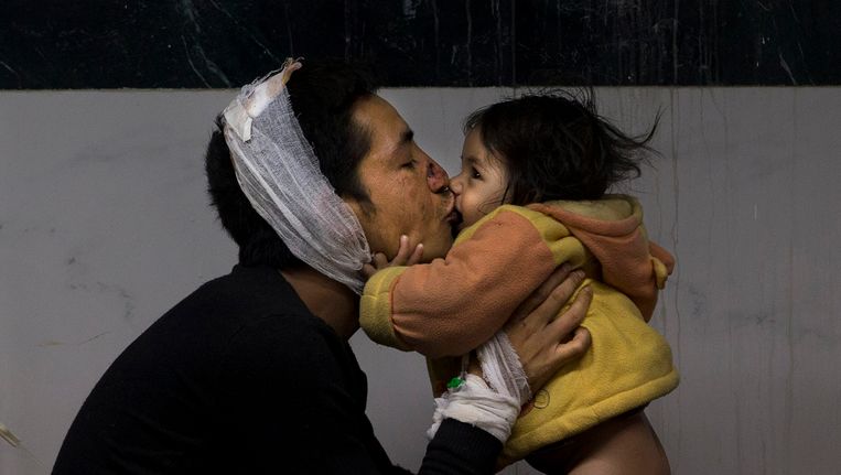 Een gewonde Nepalese man kust zijn dochtertje in een ziekenhuis in Kathmandu Beeld ap