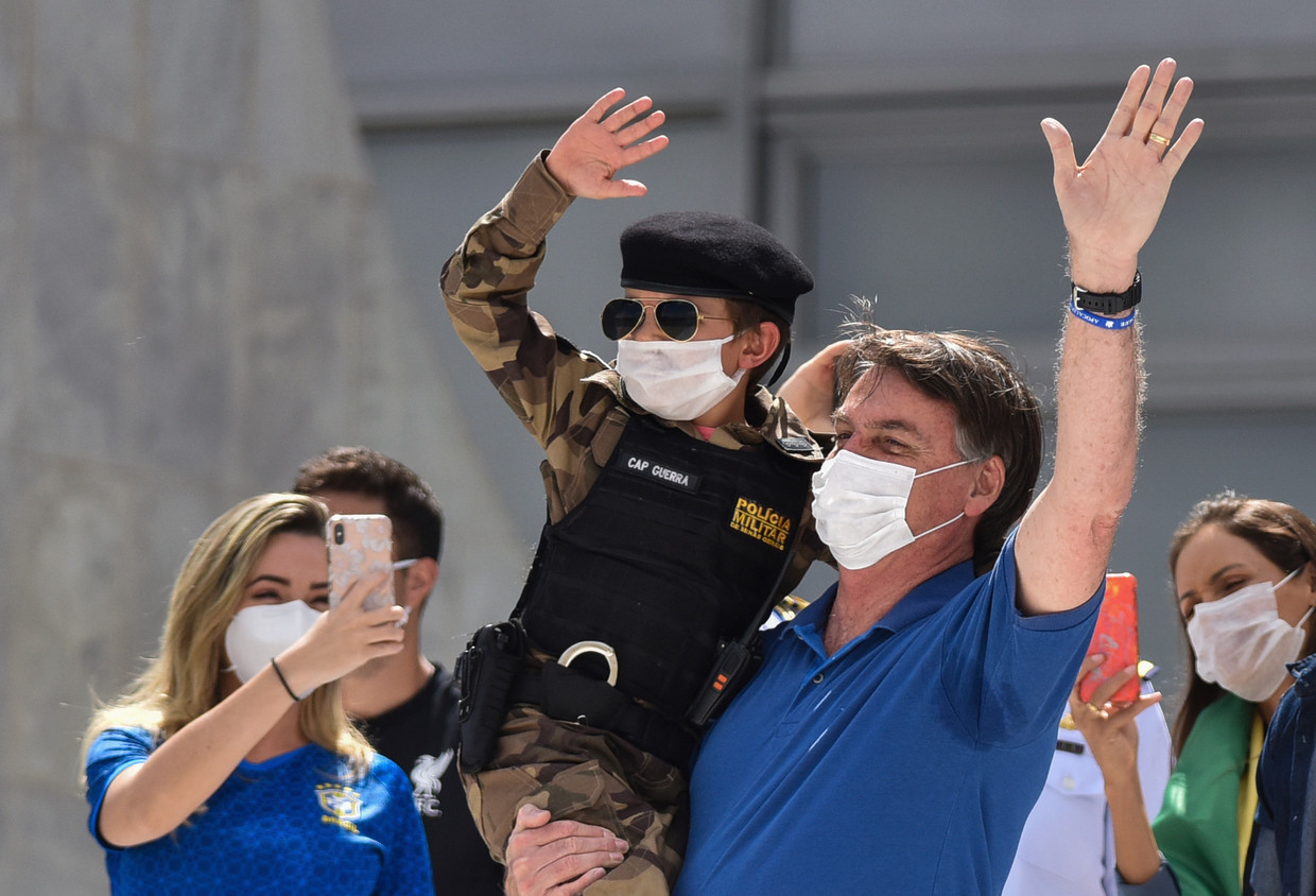 De Braziliaanse president Bolsonaro neemt het zo nauw niet met de social distancing. Zondag verscheen hij voor een menigte supporters en nam hij zelfs een paar kinderen op de arm. Beeld AP