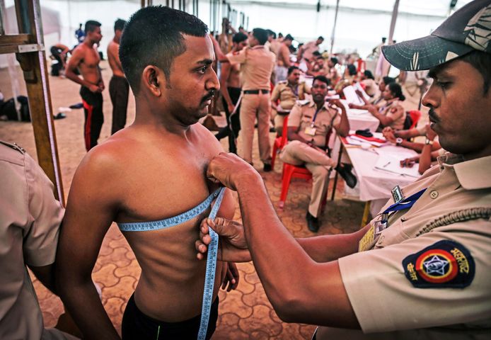 Een Indiase politie-ambtenaar meet de borstkas van een sollicitant voor de functie van politieagent in Thane, aan de rand van Mumbai. Bijna 50.000 kandidaten solliciteerden voor de 238 posten in Thane City. Foto Divyakant Solanki