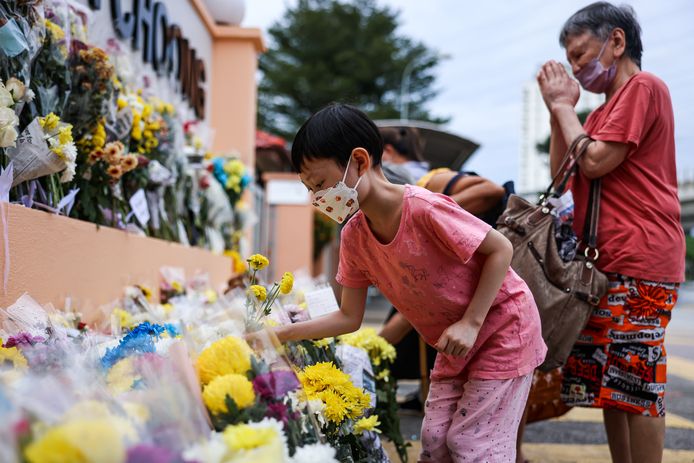 Mensen leggen bloemen om de slachtoffers te eren.