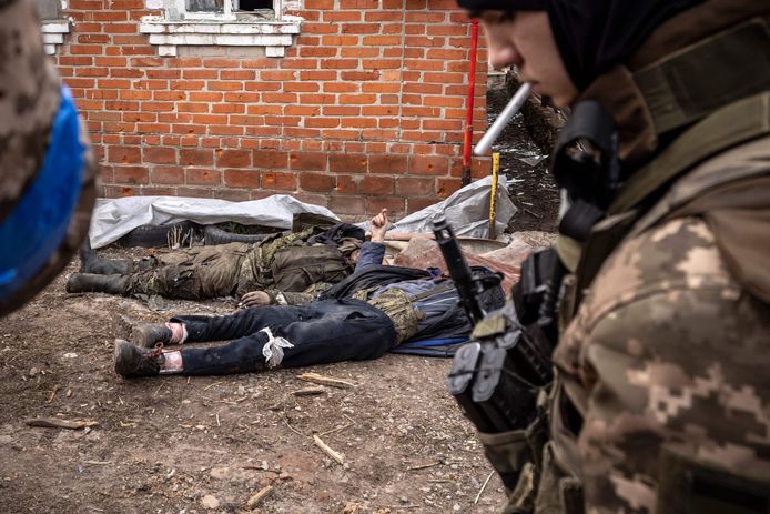 Een Oekraïense militair bij de lichamen van twee dode Russische militairen in Charkov.