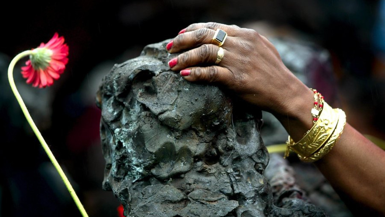 Een vrouw legt haar hand op het monument Slavernijverleden in het Oosterpark. Beeld anp