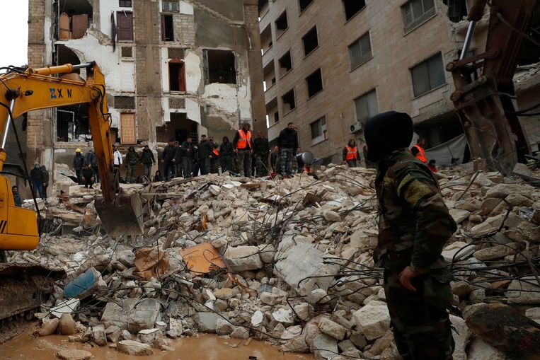 Veiligheidstroepen doorzoeken de wrakstukken van ingestorte gebouwen in Hama, Syrië. Beeld AP