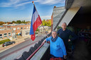 Willy en Marietje van de Valk met een omgekeerde vlag op het balkon van hun appartement tegenover gemeenschapshuis Nia Domo in Boekel. ,,Als we nog jong waren, zouden we meteen emigreren; zo ontevreden zijn we over Nederland.”