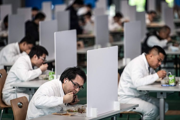 Medewerkers van een autofabriek in Wuhan tijdens hun lunchpauze. De stad is voor een groot deel weer heropend na een lockdown van maanden. Beeld AFP