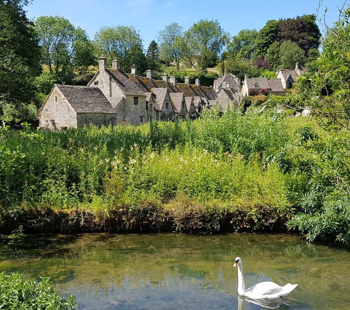 Klassieke Engelse huisjes en een watertje met een zwaan in het dorp Bibury. Vakantie in de prachtige streek Cotswold.