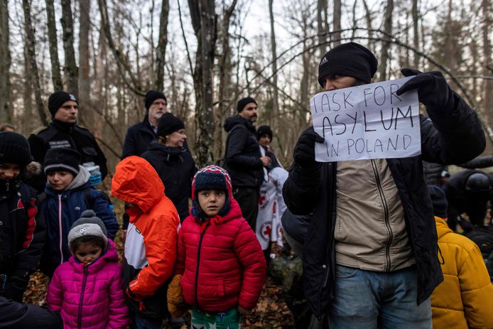 Een familielid van de 16-koppige Koerdische familie uit Irak houdt een bordje omhoog met de tekst ‘ik vraag om asiel in Polen’.