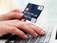 Extreme close up of female hand typing o keyboard with credit card.