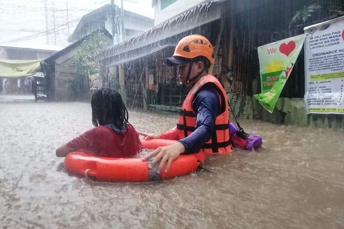 Een lid van de Filipijnse kustwacht helpt een door overstromingen getroffen bewoner, nadat supertyfoon Rai eerder al hevige regen bracht. Daardoor zijn rivieren uit hun oevers getreden.