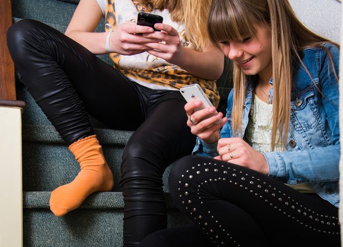 Twee meisjes spelen met hun smartphone.