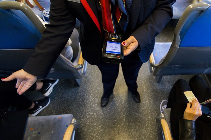 Een conducteur van de NS controleert vervoerbewijzen in een treincoupé.