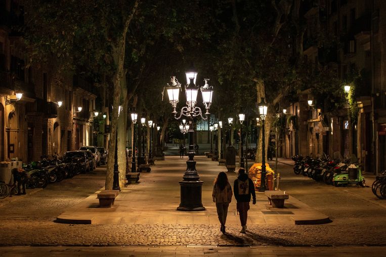 Mensen wandelen over de lege Passeig del Born tijdens de avondklok in Barcelona. Premier Sanchez kondigde zondag de noodtoestand af in Spanje, om de verspreiding van het coronavirus tegen te gaan.  Beeld EPA