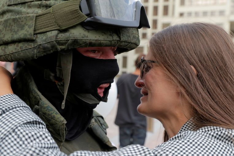 Een demonstrant omhelst een Belarussische militair. Beeld REUTERS