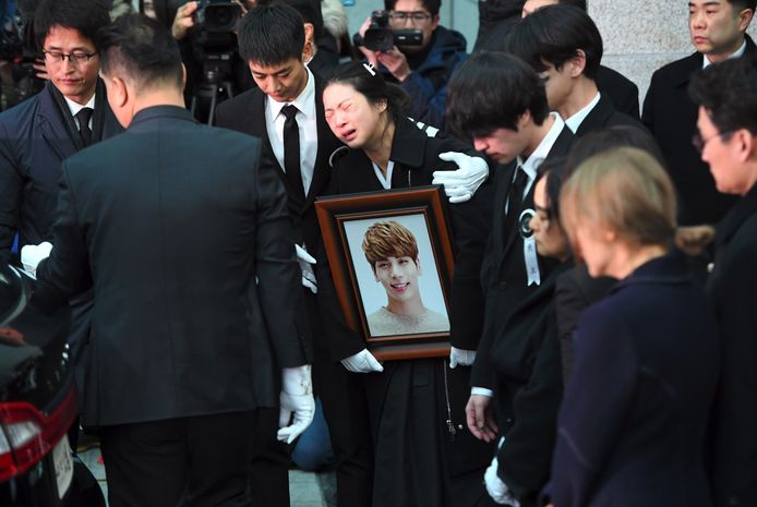 Familieleden van Kim Jong-Hyun huilen wanneer hij naar buiten wordt gedragen.