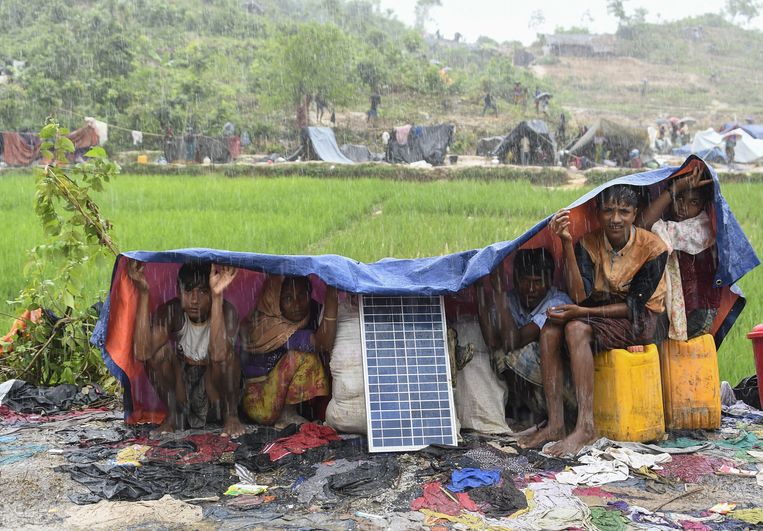 Vluchtelingen uit Myanmar, net aangekomen in het kamp Balukhali in Bangladesh, schuilen met hun spullen voor de moessonregen. Beeld AFP