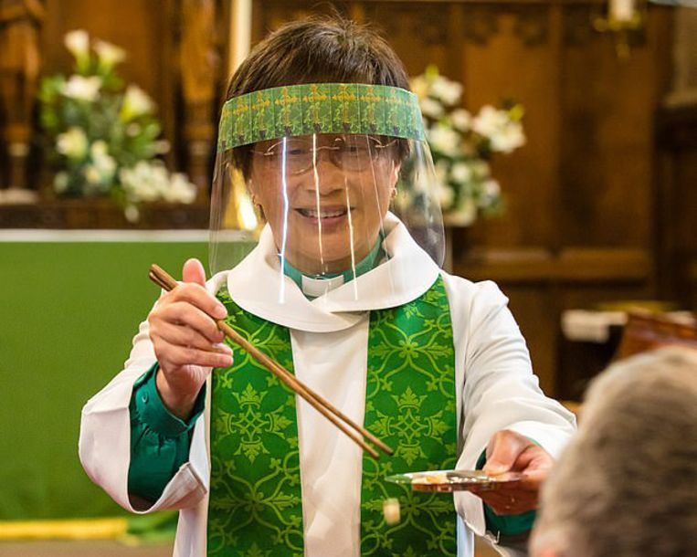 De Anglicaanse priester Eileen Harrop biedt de hostie aan met eetstokjes. Beeld PA Media